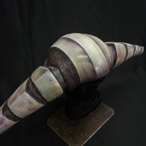 May include: A detailed, hand-painted, gray and white striped, ceramic sculpture of a creature with a long, curved, segmented body. The sculpture is mounted on a metal base.