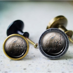 Puede incluir: Dos pomos de armario con acabado negro y latón. Los pomos presentan un diseño redondo, gris y marrón con aspecto de mármol.