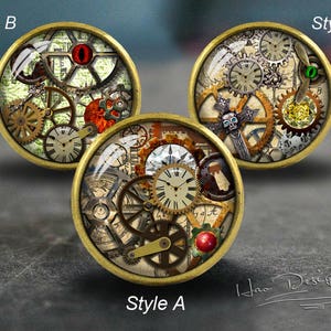 Op de afbeelding: Drie ronde, messingkleurige decoratieve knoppen met een steampunk-ontwerp. Elke knop heeft een ander ontwerp met tandwielen, wijzerplaten en andere ingewikkelde details. De knoppen zijn gelabeld met "Style A", "Style B" en "Style C".
