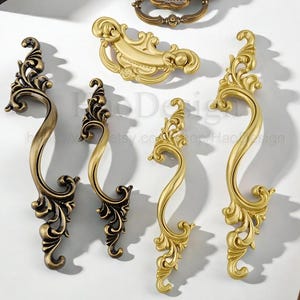May include: An assortment of ornate, antique-style cabinet hardware in various shades of gold and bronze. The collection includes handles and pulls with intricate floral and scroll designs, perfect for adding a touch of elegance to furniture.