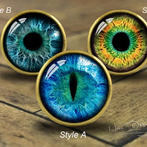 May include: Three different styles of decorative glass eyes with gold metal frames. The eyes are blue, green, and yellow with black pupils.