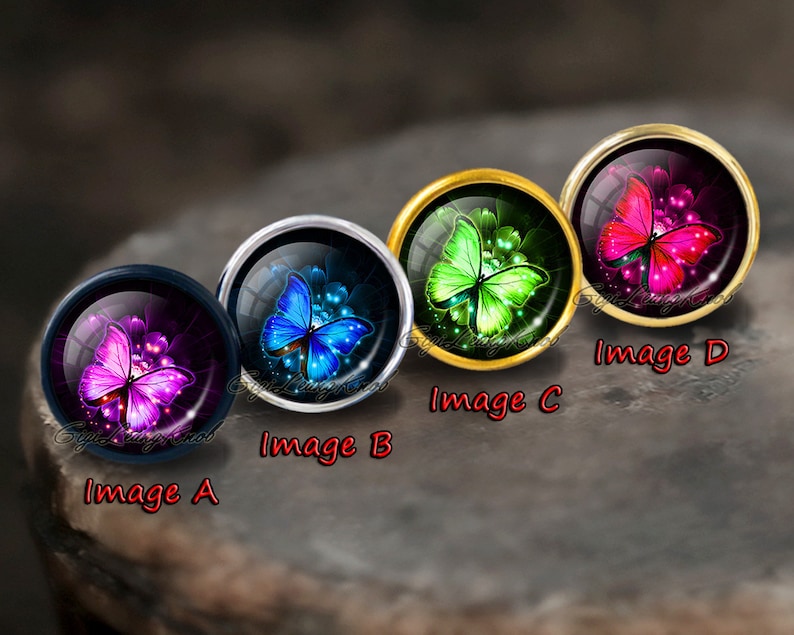 Puede incluir: Cuatro cabochones redondos de vidrio con engastes dorados, plateados y negros, cada uno con una mariposa de color diferente con alas iridiscentes. Las mariposas son rosa, verde, azul y morado.