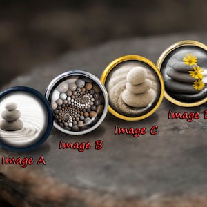 May include: Four round, decorative, metal,  cabochons with different images of stacked stones. The images are labelled "Image A", "Image B", "Image C", and "Image D".
