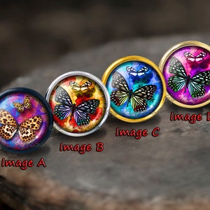 Pode incluir: Quatro caboch&otilde;es redondos de vidro com diferentes desenhos de borboletas. Os caboch&otilde;es est&atilde;o engastados em montagens de metal e est&atilde;o dispostos em fila. As borboletas s&atilde;o coloridas e t&ecirc;m detalhes intrincados. Os caboch&otilde;es s&atilde;o etiquetados como A, B, C e D.
