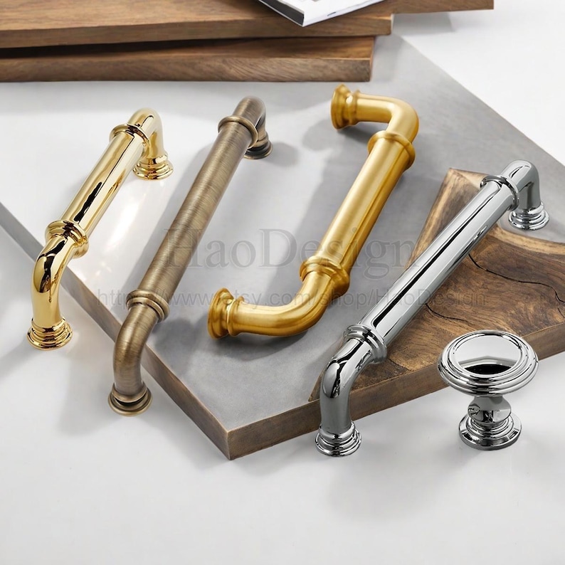 May include: An assortment of cabinet hardware in various metallic finishes. The selection includes gold, bronze, and silver handles, along with a matching silver knob. The hardware features a classic, elegant design, suitable for kitchen or furniture upgrades.