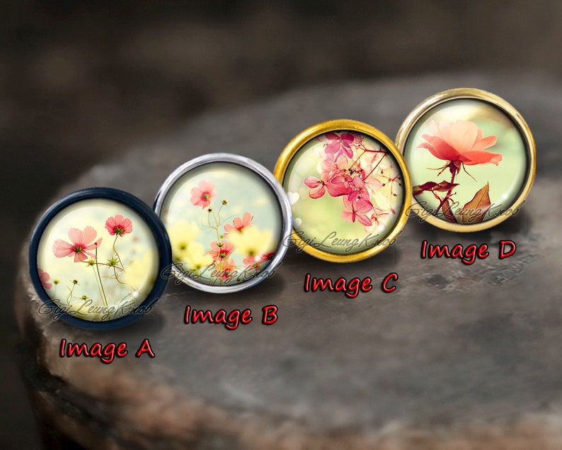 Puede incluir: Cuatro cabochons redondos de vidrio con diferentes im&aacute;genes florales. Los cabochons est&aacute;n engastados en monturas met&aacute;licas con acabado dorado, plateado y negro. Las im&aacute;genes incluyen flores rosas, flores blancas y una sola rosa rosa.