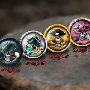 May include: Four round skull themed cabochons with different designs. The first cabochon has a blue skull wearing a hat with a white flower. The second cabochon has a skull wearing a hat with blue butterflies. The third cabochon has a skull with a pirate hat and crossbones. The fourth cabochon has a skull wearing a pink hat with a pink flower.