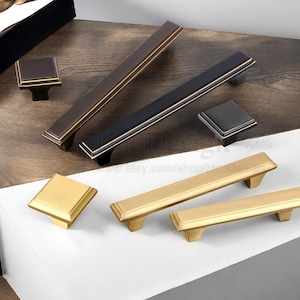May include: An assortment of cabinet hardware, including square knobs and rectangular pulls. The hardware is available in various finishes, including gold, black, and bronze. The pulls range in length.