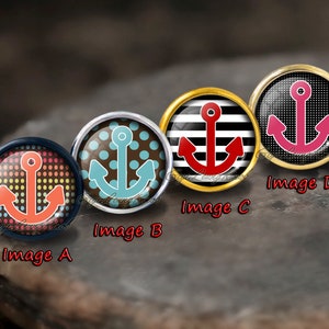 May include: Four round, decorative, glass cabochons with different anchor designs. The anchors are red, blue, pink, and red. The cabochons are set in silver, gold, and black metal settings. The cabochons are labelled Image A, Image B, Image C, and Image D.
