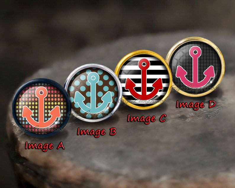 May include: Four round, decorative, glass cabochons with different anchor designs. The anchors are red, blue, pink, and red. The cabochons are set in silver, gold, and black metal settings. The cabochons are labelled Image A, Image B, Image C, and Image D.