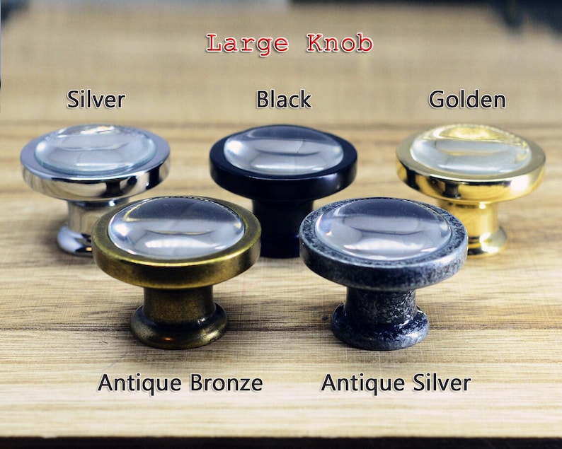 以下が含まれることがあります： 透明なガラスのトップと金属製のベースを持つ5つのキャビネットノブ。ノブの色はシルバー、ブラック、ゴールド、アンティークブロンズ、アンティークシルバーです。
