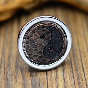 Puede incluir: Un anillo de plata con un símbolo yin yang de cobre martillado y negro.