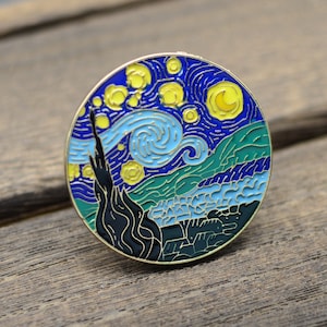May include: A round enamel pin depicting Vincent van Gogh's famous painting, "Starry Night". The pin is blue, yellow, green, and black.