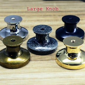 以下が含まれることがあります： 5つの異なる仕上げのキャビネットノブ: 光沢のあるクロム、アンティークブラス、ブラック、2色のグレー。ノブは丸型で、中央が盛り上がり、ベースはフラットです。画像の上部に「Large Knob」というテキストが表示されています。