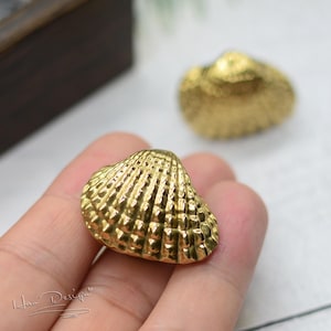 May include: A pair of gold-coloured seashell earrings. The seashells are detailed with a textured, ribbed design.