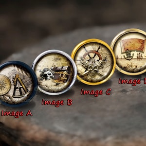 Pode incluir: Quatro cabochons redondos de vidro decorativos com tema náutico. Cada cabochon apresenta uma imagem diferente: uma bússola e um transferidor, uma caveira e ossos cruzados com um baú do tesouro, uma caveira e ossos cruzados com um leme de barco e um mapa com um barco e uma âncora.