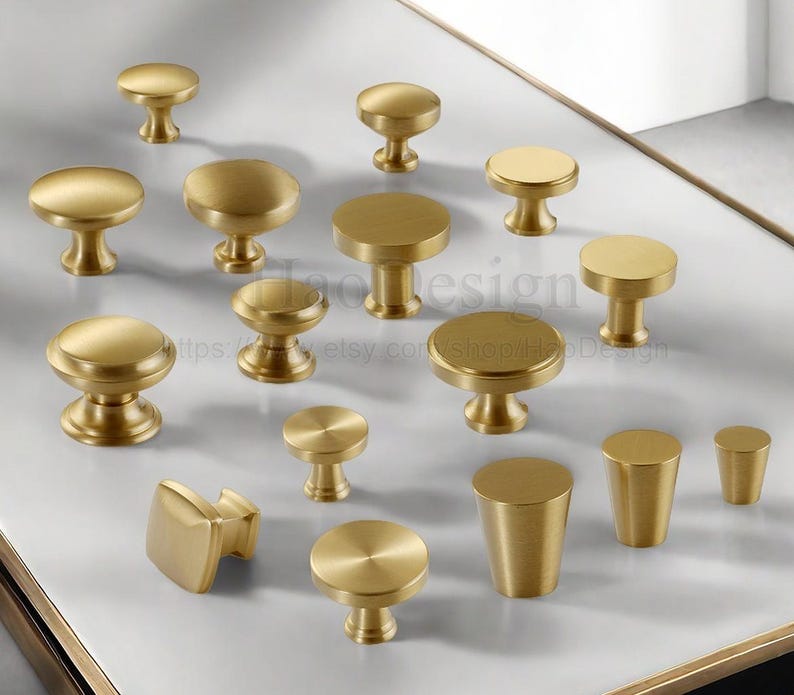 Puede incluir: Una colecci&oacute;n de pomos y tiradores dorados para armarios de varias formas. Los pomos presentan dise&ntilde;os redondos, cuadrados y cil&iacute;ndricos. Algunos tienen forma de hongo, mientras que otros son m&aacute;s minimalistas.