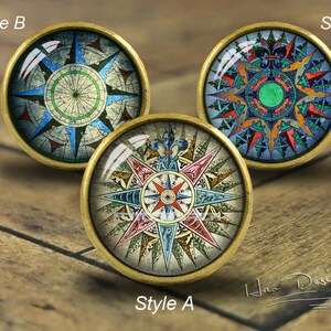 Può includere: Tre diversi stili di pomelli per armadi a tema bussola con finitura dorata. I pomelli presentano un design vintage con dettagli intricati e una varietà di colori, tra cui blu, rosso, verde e giallo.