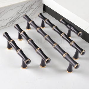 May include: Set of black bamboo-style cabinet pulls with gold accents. These decorative handles feature a bamboo stalk design, adding a natural and elegant touch to furniture. The pulls are designed for easy installation and are suitable for various cabinet styles.