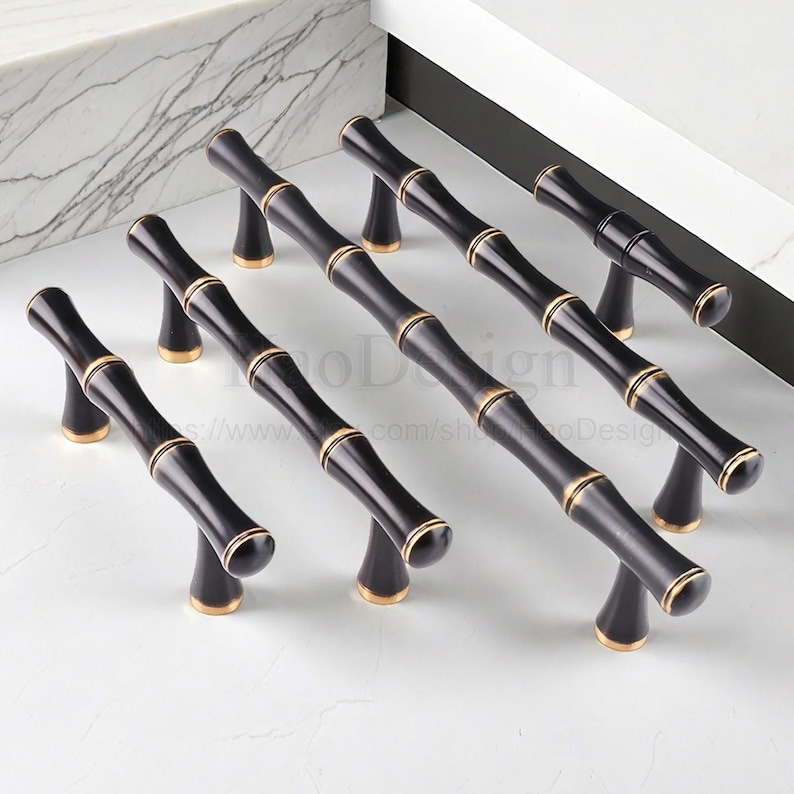May include: Set of black bamboo-style cabinet pulls with gold accents. These decorative handles feature a bamboo stalk design, adding a natural and elegant touch to furniture. The pulls are designed for easy installation and are suitable for various cabinet styles.