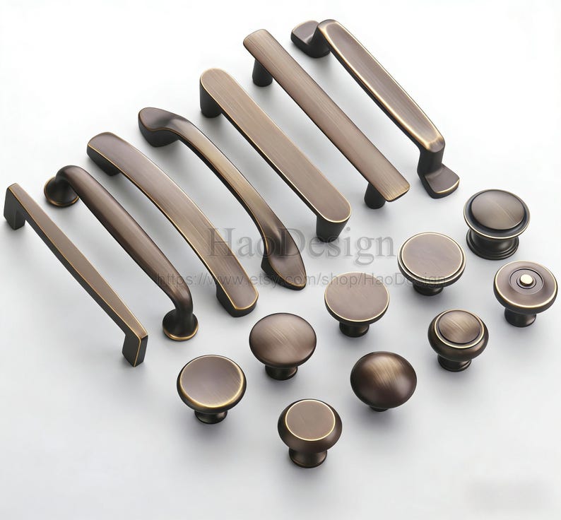May include: A selection of bronze-coloured cabinet hardware, featuring a range of handle styles and round knobs. The handles include straight bars and curved pulls. The knobs have a simple, rounded design. All pieces have a vintage aesthetic.