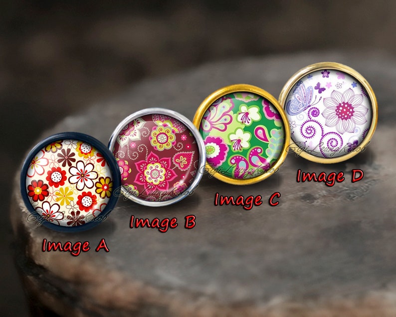 May include: Four round, decorative cabochons with floral patterns. The cabochons are set in metal settings with a gold, silver, and black finish. The floral patterns feature a variety of colours, including red, pink, green, white, and yellow.