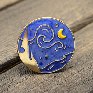 以下が含まれることがあります： 星が輝く夜空に三日月と渦巻く雲が描かれた、金色の縁取りのある青いエナメル製のピンバッジです。