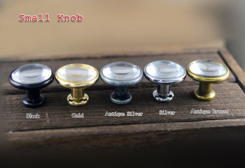 以下が含まれることがあります： 黒、金、アンティークシルバー、シルバー、アンティークブロンズなど、さまざまな仕上げの金属製ベースが付いた、小さな丸いガラス製のノブが5つあります。  "Small Knob"という文字がノブの上に書かれています。