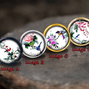 以下が含まれることがあります： 金、銀、黒の金属製の枠にセットされた、丸い装飾的なセラミックのカボションが4つあります。各カボションは、白い背景に鳥と花が描かれた異なる画像を特徴としています。画像は伝統的な中国風です。