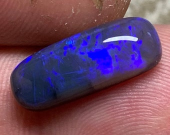 May include: A dark blue and black oval-shaped opal gemstone with iridescent flashes of color.