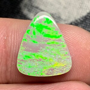 May include: A triangular, green and white opal gemstone with a unique, swirling pattern.