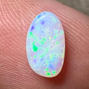 May include: Oval-shaped white opal gemstone with green, blue, and purple iridescent flashes.