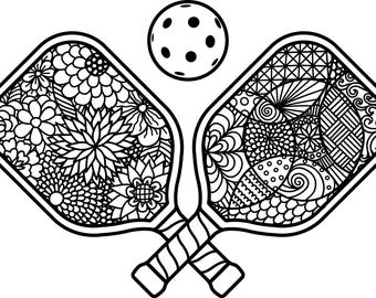 Op de afbeelding: Zwart-wit illustratie van twee pickleball rackets met decoratieve bloemen- en geometrische patronen, gekruist bij de handvatten, en een gestippelde bal erboven. De rackets zijn gedetailleerd met ingewikkelde ontwerpen.