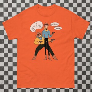 May include: Orange t-shirt featuring a cartoon illustration of two figures in cowboy hats and boots, holding guns. One figure has a Star Trek uniform. Speech bubbles say "Yeehaw!" and "As he said, 'Yee-haw.'"