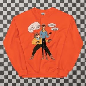 May include: Orange sweatshirt with a cartoon illustration of two figures in cowboy hats and boots, holding guns. One figure says "YEE HAW!" in a speech bubble, the other says "Yee-Haw" in a speech bubble. The sweatshirt has the brand name "Gildan".