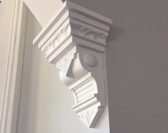 May include: White painted wooden corbel with intricate carvings and a decorative design. The corbel is mounted on a white wall.