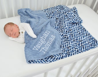 May include: A soft, textured blue blanket with raised dots and the embroidered name Vaughan Thomas. The blanket features a contrasting white and blue geometric pattern on the reverse side, providing a dual-textured appearance for comfort.