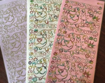 May include: Three sheets of holographic stickers featuring a cartoon pig wearing sunglasses and a marijuana leaf. The stickers are pink, white, and purple and have the text "Hemphog" and "Pot Peace" on them.