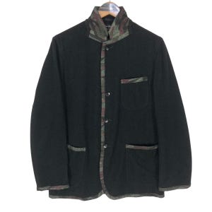 May include: A black jacket with a camouflage pattern on the collar, trim, and pocket. The jacket has three buttons and two front pockets. The jacket is hanging on a wooden hanger.