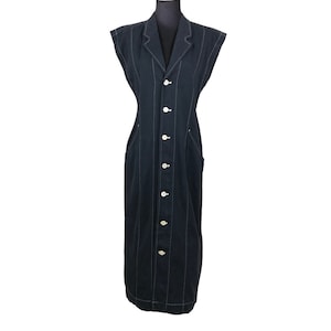May include: A sleeveless, black dress with white pinstripes and a notched collar. The dress features a button-down front with white buttons and two front pockets. The dress is displayed on a black mannequin.