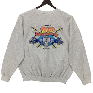May include: A light gray sweatshirt with a graphic on the back featuring the text "12th Annual Mayo Longboard Winter Classic". The graphic includes crossed surfboards, flowers, and a surfer.