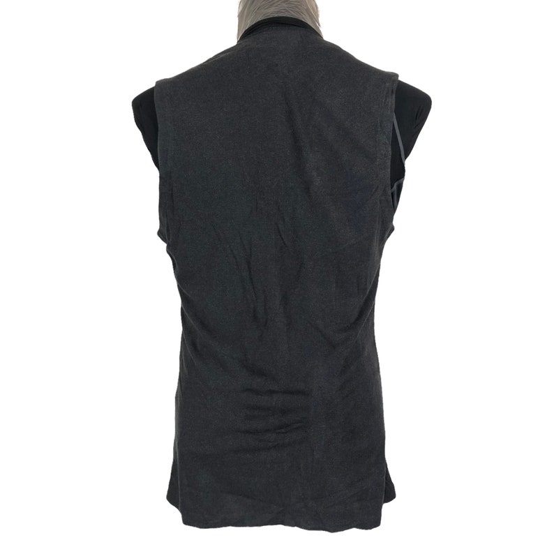 May include: A dark gray vest with a V-neck collar. The vest is sleeveless and appears to be made of a soft, textured fabric. The back of the vest is visible, and it is displayed on a black mannequin.