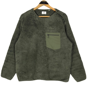 Puede incluir: Jersey de forro polar verde oliva con un pequeño bolsillo con cremallera en el pecho. La parte superior de manga larga tiene cuello redondo y un aspecto texturizado y difuso. La prenda está colgada de una percha de madera.
