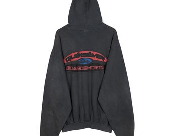 May include: A black hooded sweatshirt with the Quiksilver logo in red, blue, and white across the back. The sweatshirt has a drawstring hood and a kangaroo pocket. The words "BOARDSHORTS" are below the logo.