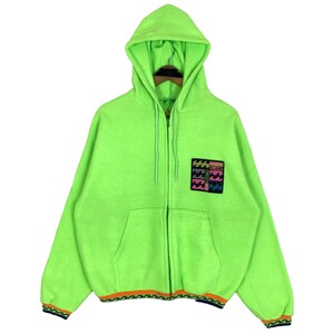 May include: Bright neon green zip-up hoodie with a hood and a front pocket. The hoodie features a colorful patch on the chest with the brand name. The cuffs and hem have a patterned trim. The hoodie is made of a soft, fuzzy material.
