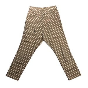 Puede incluir: Pantalones marrones con lunares blancos. Los pantalones tienen cintura alta, bolsillos y cierre de botón. Los lunares están espaciados uniformemente sobre la tela.