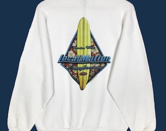 May include: White sweatshirt with a graphic featuring a yellow surfboard inside a diamond-shaped design. The design includes the words "Hawaiian Woody" and "Local Motion Longboards" in blue and red lettering, with floral accents.