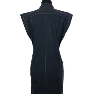 May include: A sleeveless black dress with white stitching details. The dress has a collared neckline and a button-down front. The white stitching outlines the seams and edges of the dress, creating a contrasting design. The dress is displayed on a mannequin.