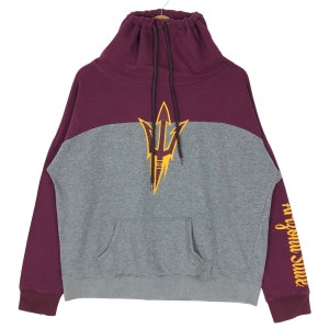 May include: A maroon and gray sweatshirt with a high, drawstring collar. The front features a gold trident logo. The right sleeve has the text "Arizona State" in gold. The sweatshirt has a kangaroo pocket.