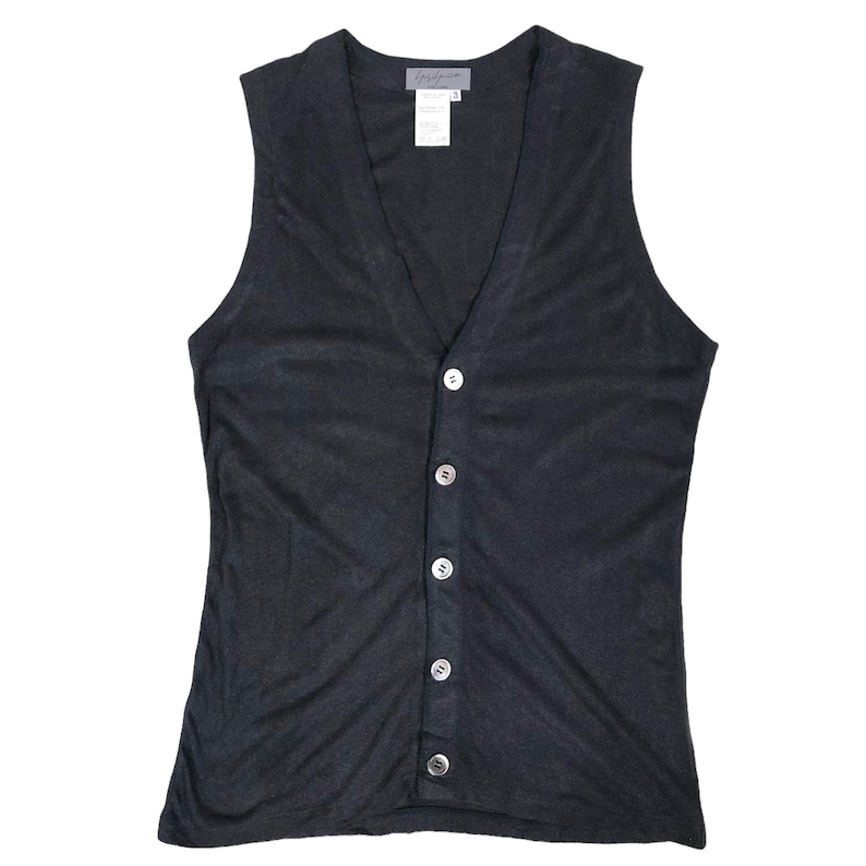 May include: A dark gray sleeveless button-up vest with a V-neck. The vest has six white buttons down the front and a small tag near the neckline. The fabric appears to be lightweight and slightly textured.
